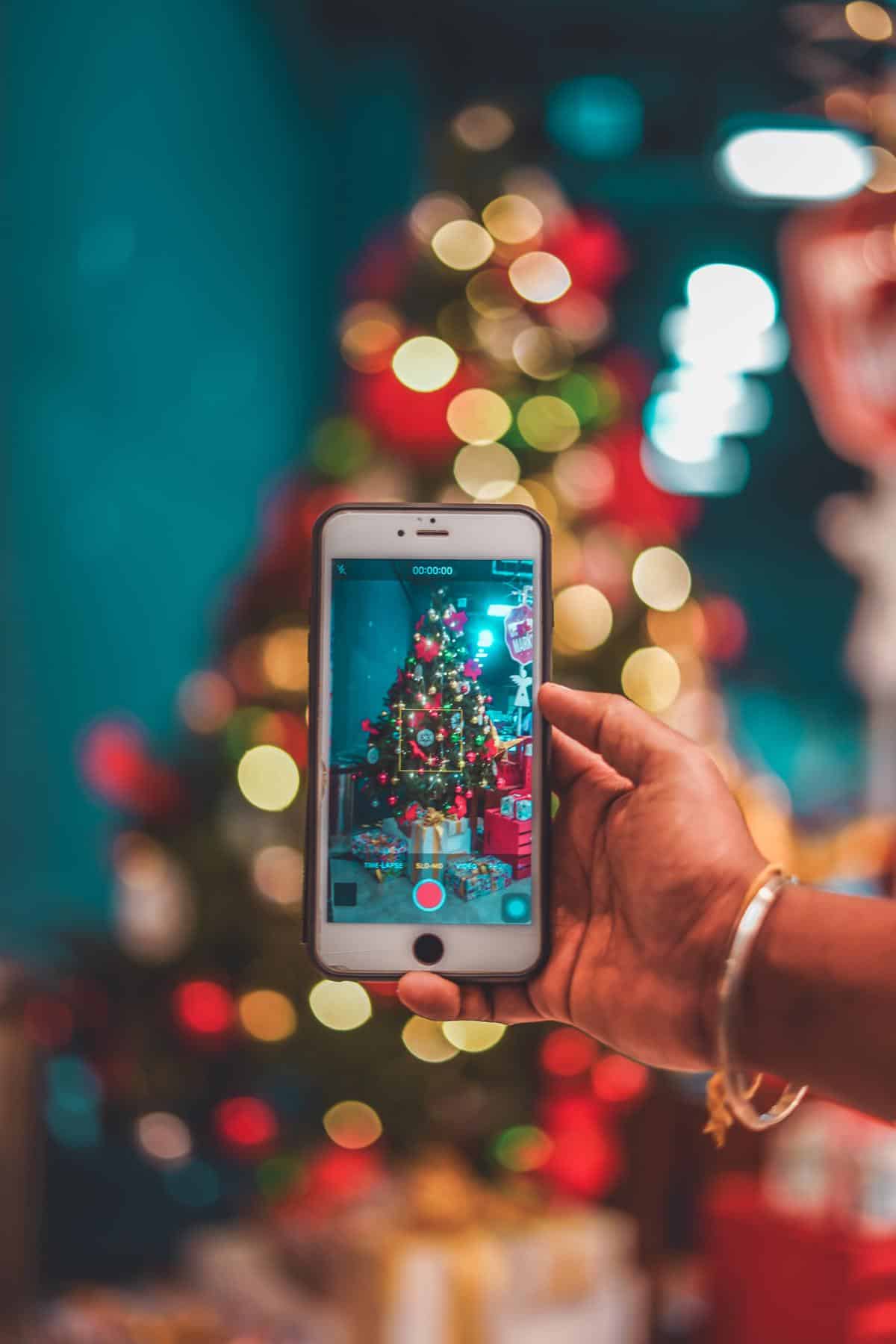 A person using a cell phone and looking at a family tree on the screen, symbolizing the connection between cell phones and devices for genealogy research.